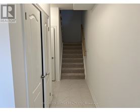 A hallway with a staircase leading to a bedroom.