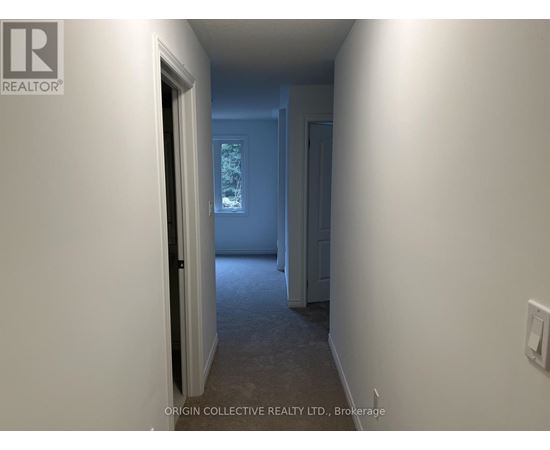 A hallway with a door on the left and a wall on the right.