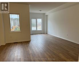 A spacious room with wooden flooring and two windows.