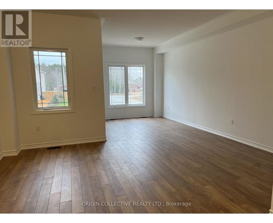 A spacious room with wooden flooring and two windows.
