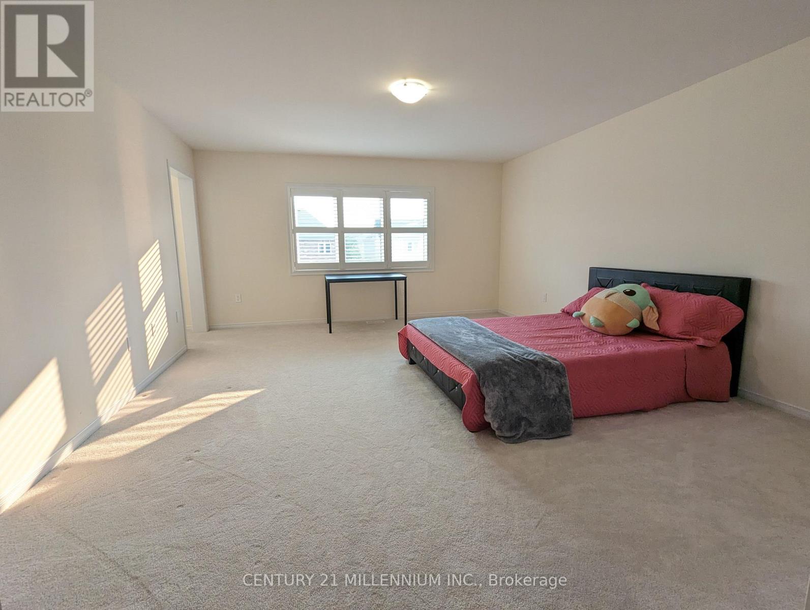 A bedroom with a bed, a desk, and a window.