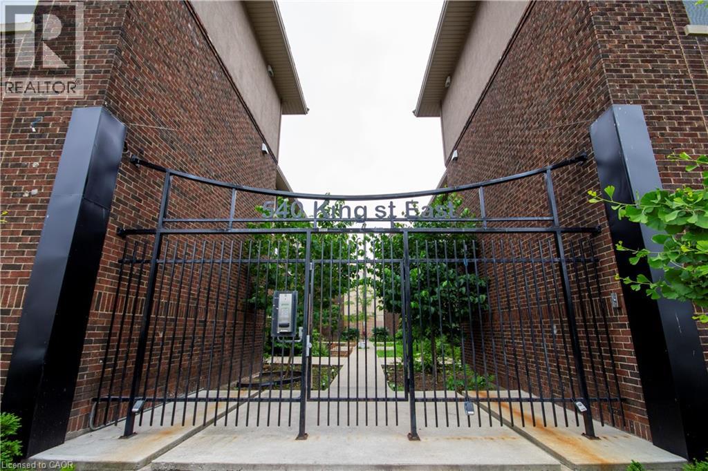 A black metal gate with a brick wall on either side.
