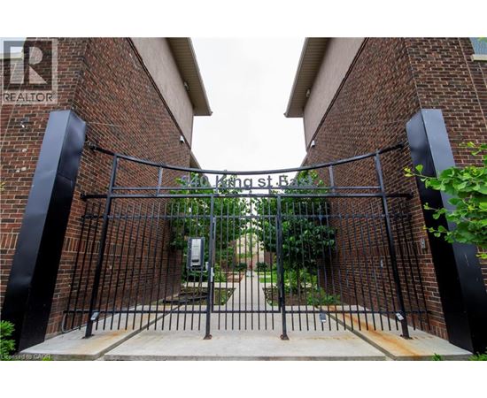 A black metal gate with a brick wall on either side.
