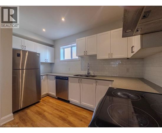 A kitchen with white cabinets and a stainless steel refrigerator.