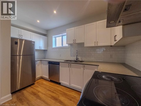 A kitchen with white cabinets and a stainless steel refrigerator.