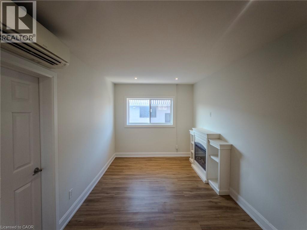 A room with wooden floors and white walls, with a window and a door.