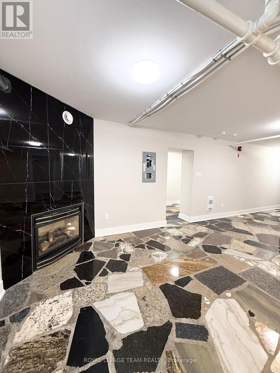A stone fireplace in a room with a black tile wall.