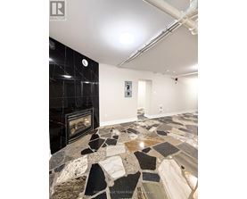 A stone fireplace in a room with a black tile wall.