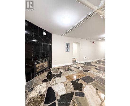 A stone fireplace in a room with a black tile wall.