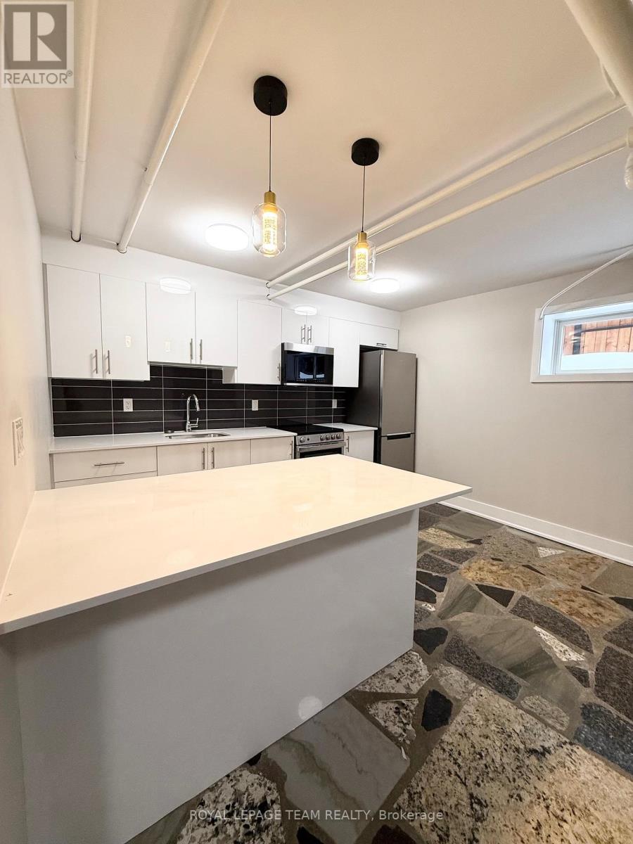 A kitchen with white cabinets and a stone floor.
