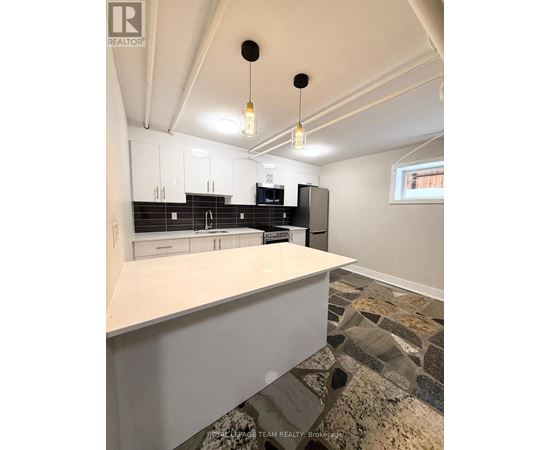 A kitchen with white cabinets and a stone floor.