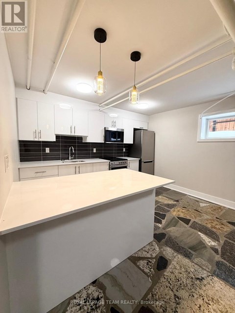 A kitchen with white cabinets and a stone floor.