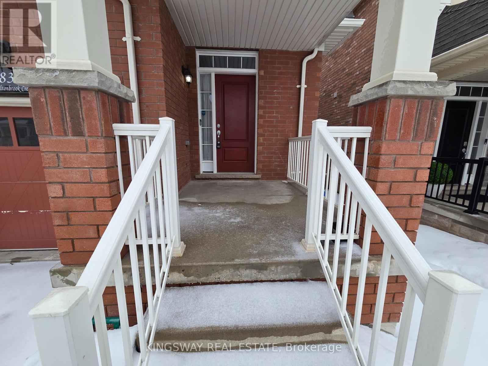 A red door is on the left side of a white railing.