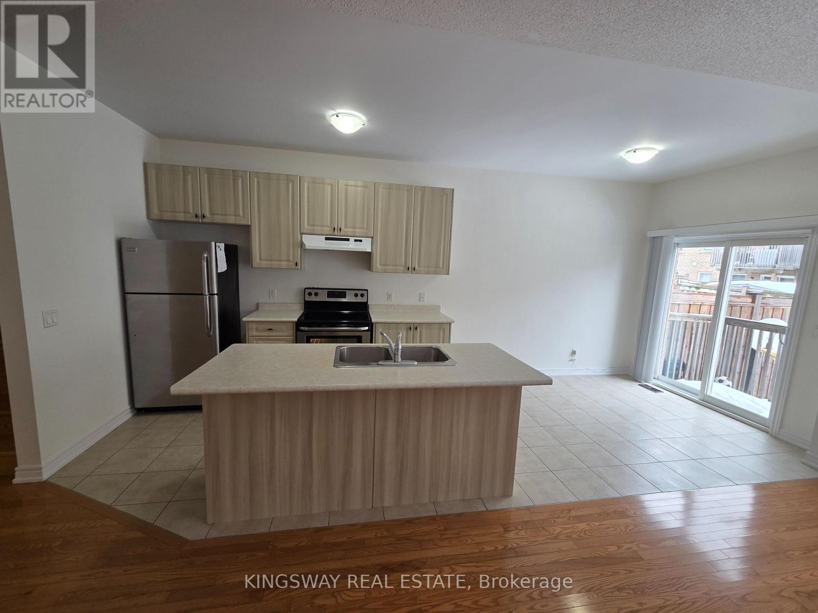 A kitchen with a refrigerator, oven, and sink is shown in a real estate listing.
