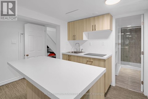 A white countertop in a kitchen with a sink and cabinets.