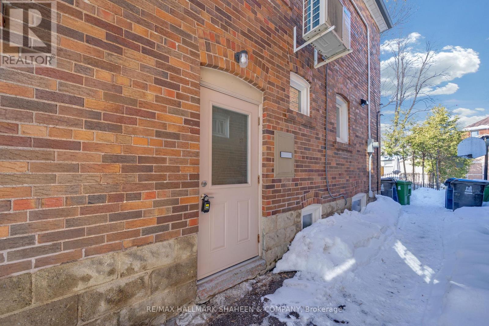 A brick building with a white door and a sign that says RE/MAX Hallmark Shadlen & Brokerage.