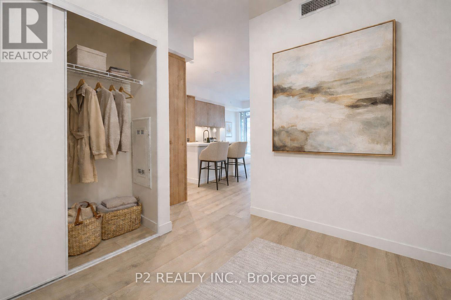 A room with a painting on the wall and a coat rack with clothes hanging on it.