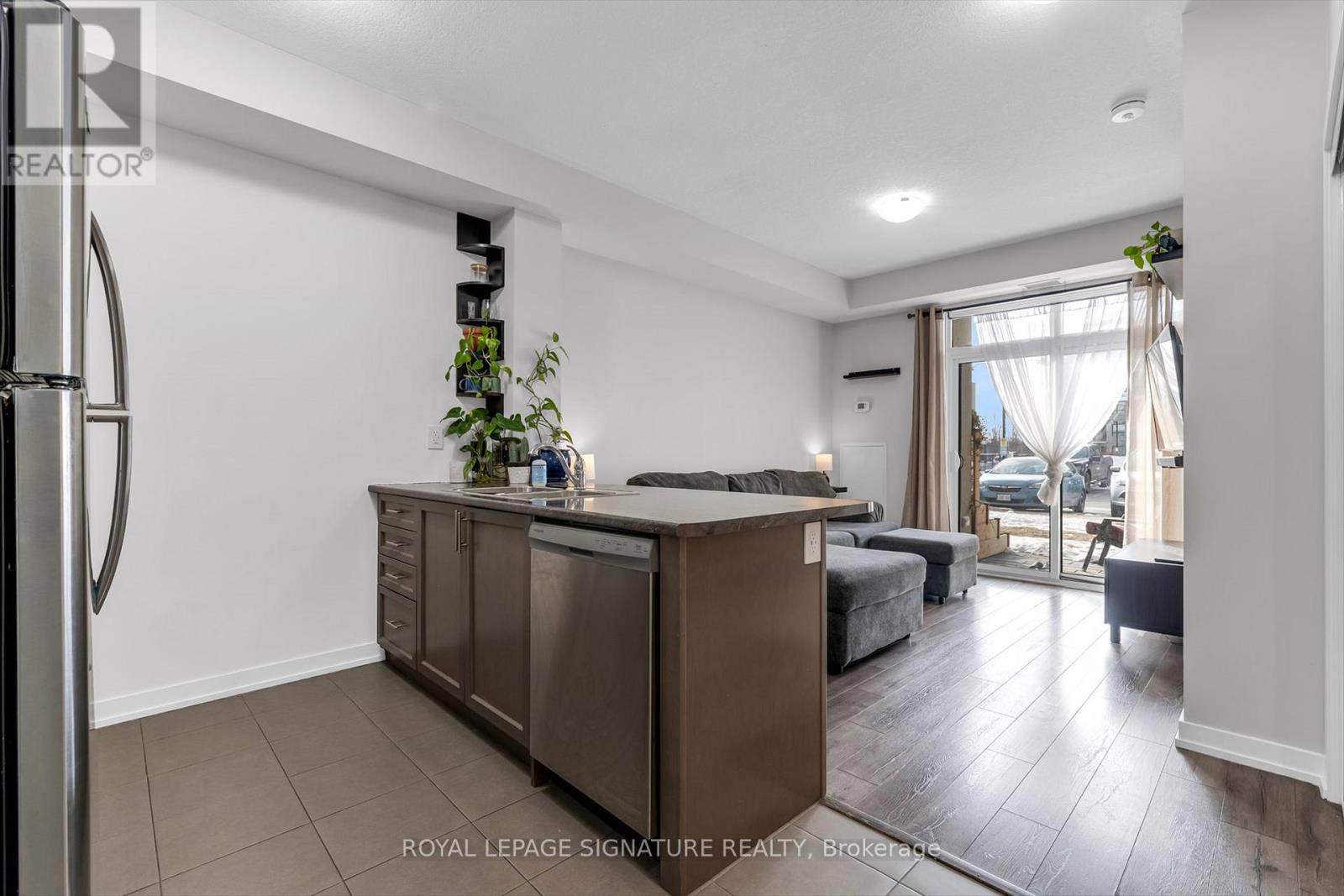 A modern kitchen with a refrigerator on the left and a dining area with a table and chairs.