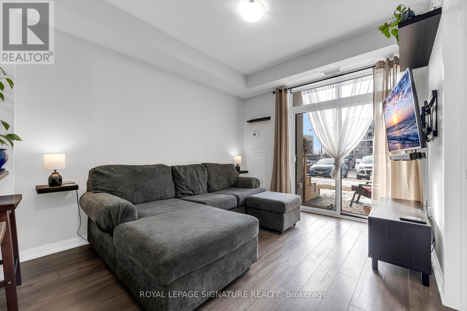 A living room with a grey couch and a television on the wall.