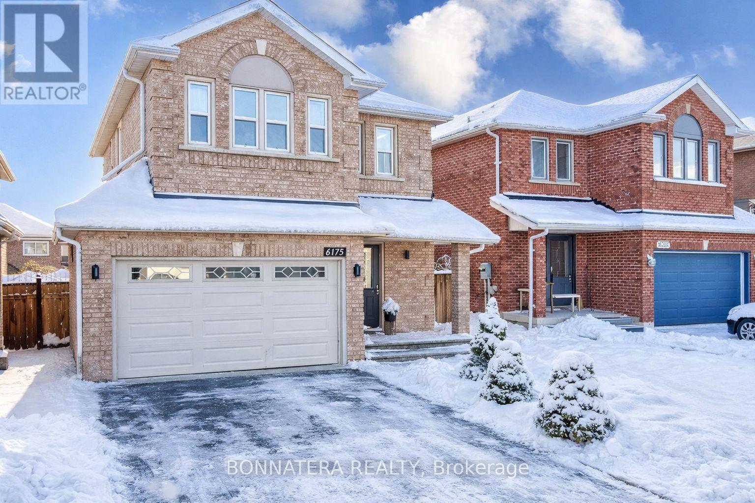 A house with a snow-covered front yard and a garage.