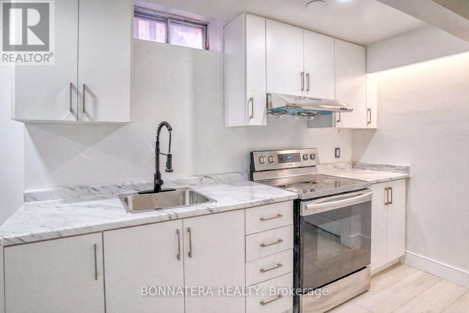 A kitchen with white cabinets and a marble countertop.