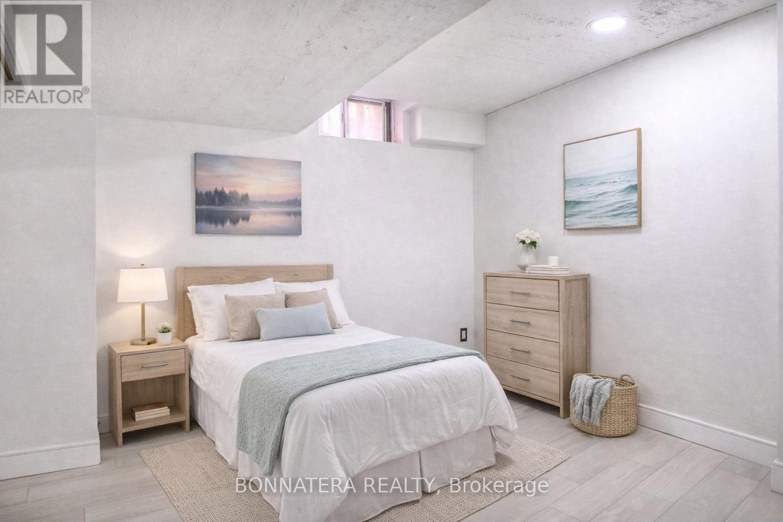 A bedroom with a large bed, a nightstand, and a painting on the wall.