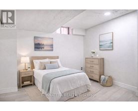 A bedroom with a large bed, a nightstand, and a painting on the wall.