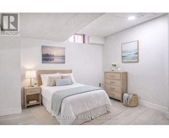 A bedroom with a large bed, a nightstand, and a painting on the wall.