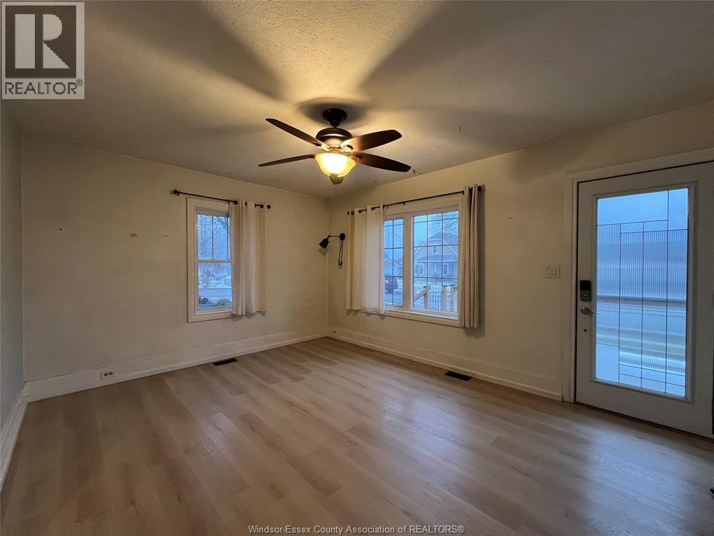 A room with a ceiling fan and two windows.