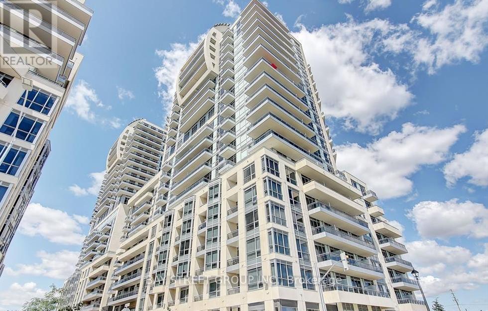 A tall residential building with balconies and a red logo on the top.