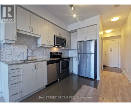 A kitchen with white cabinets and a black fridge.