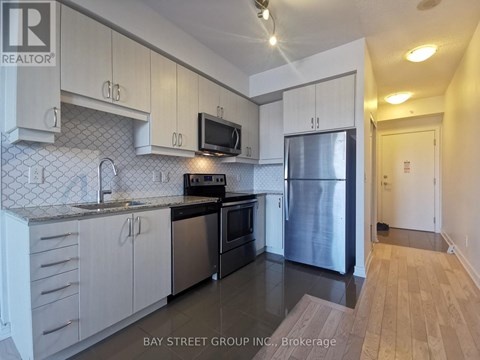 A kitchen with white cabinets and a black fridge.