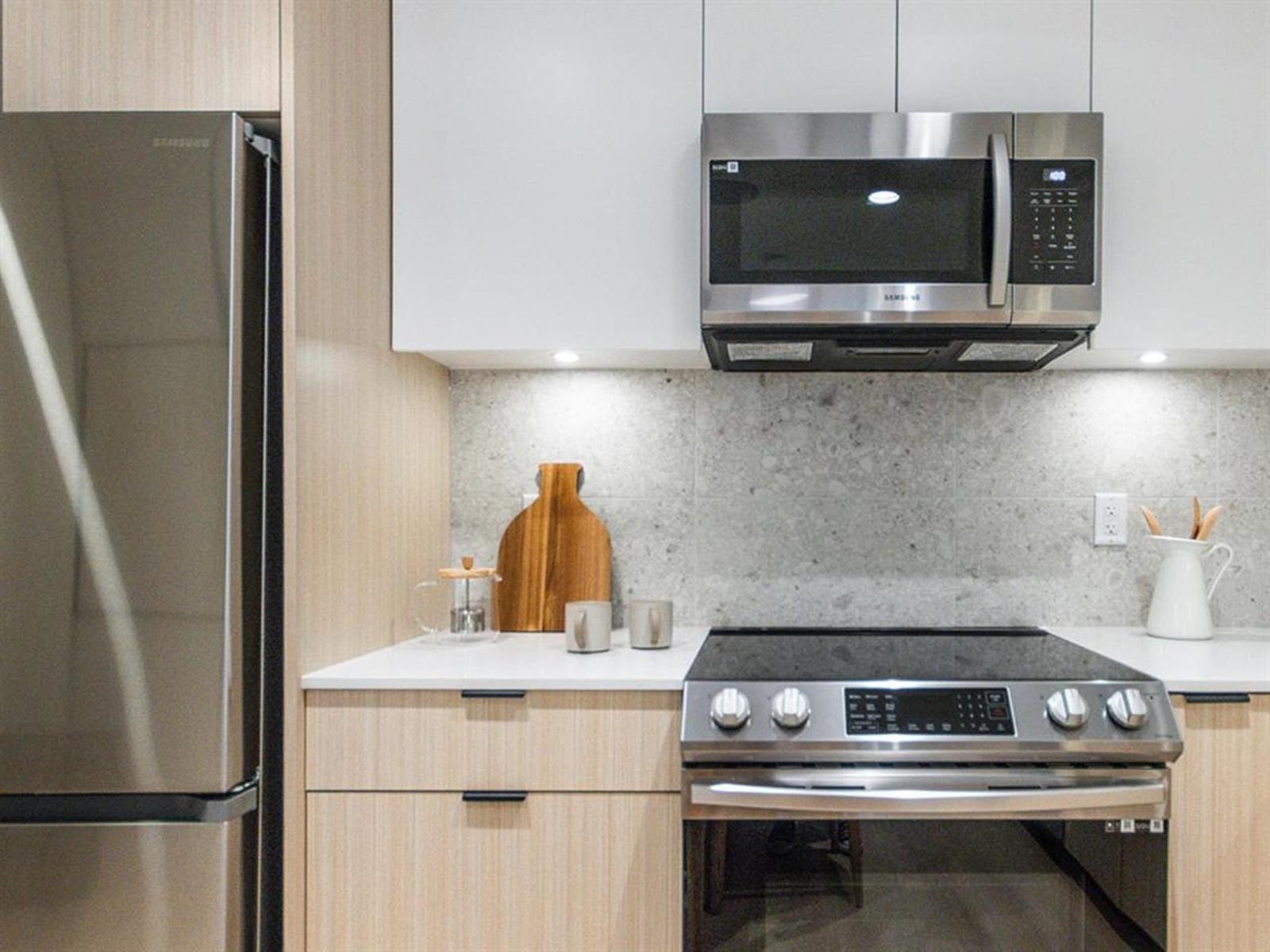 A modern kitchen with a stainless steel oven and microwave above it.