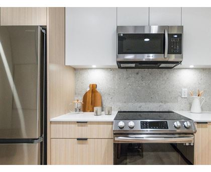 A modern kitchen with a stainless steel oven and microwave above it.