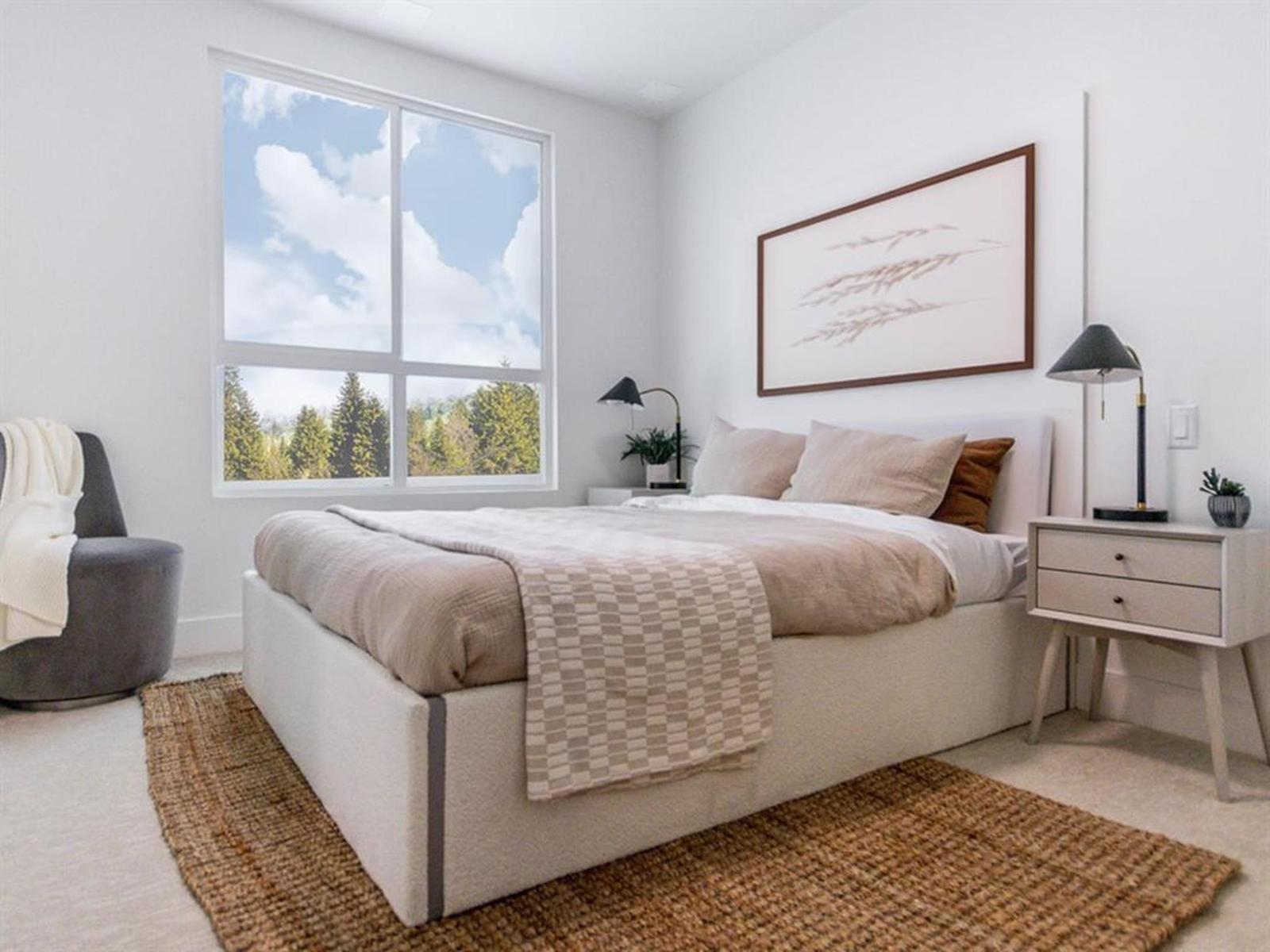 A bedroom with a large bed and a view of trees outside the window.