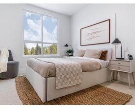 A bedroom with a large bed and a view of trees outside the window.