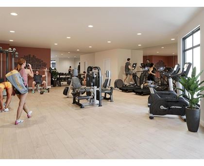 A woman is running on a treadmill in a gym with other people exercising.