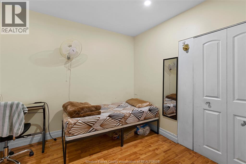 A bedroom with a bed, chair, and a fan.
