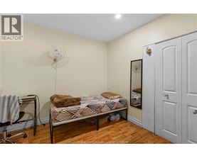 A bedroom with a bed, chair, and a fan.