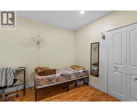 A bedroom with a bed, chair, and a fan.