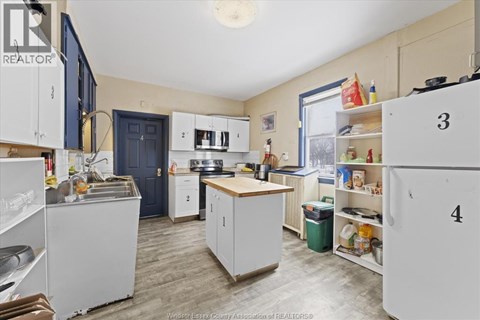 A kitchen with white cabinets and a blue door.
