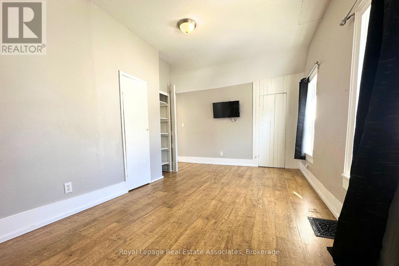 A spacious room with wooden flooring and a flat-screen TV mounted on the wall.