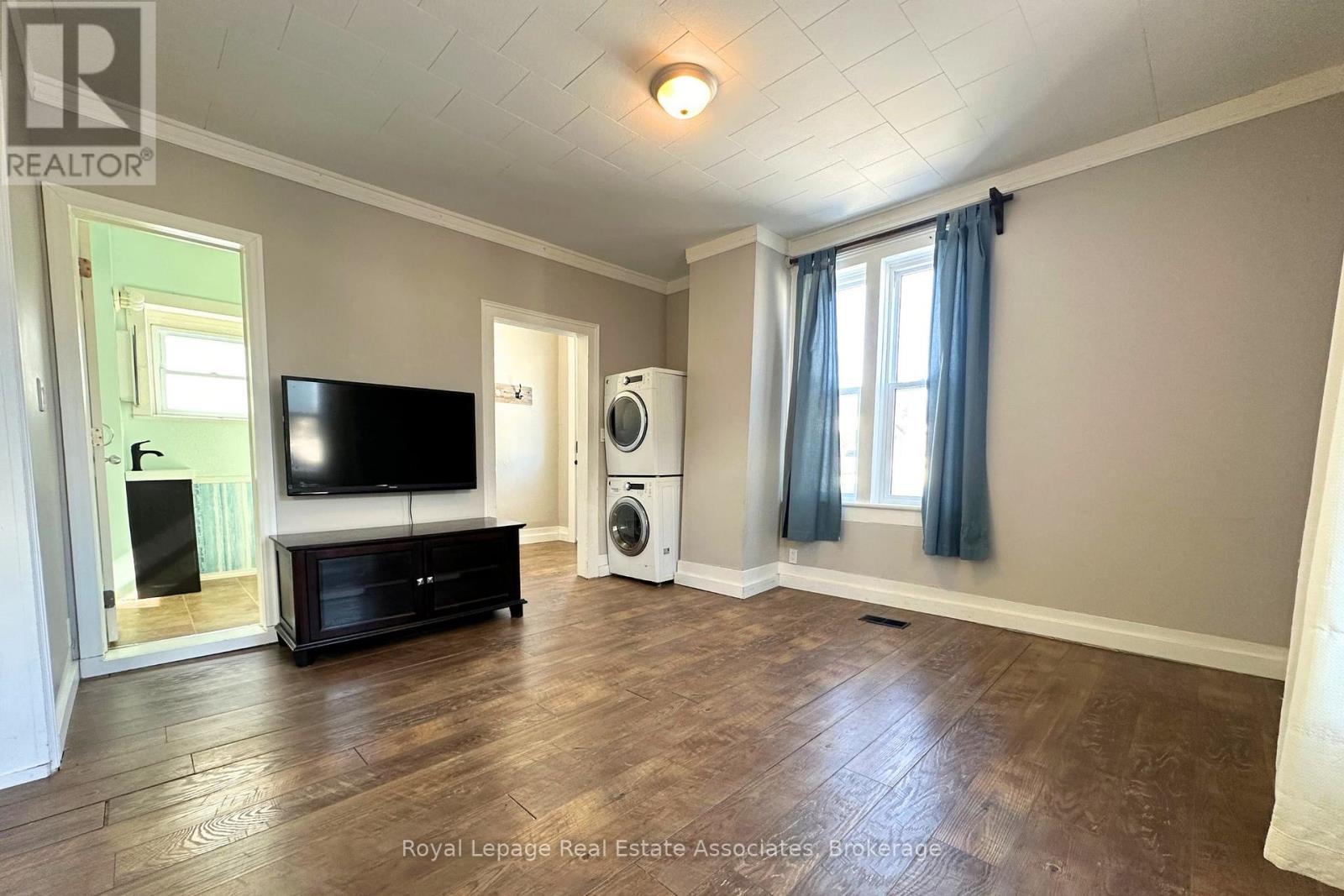 A spacious living room with a television, a black cabinet, and a washing machine.