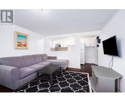 A living room with a grey couch and a painting of a beach scene on the wall.