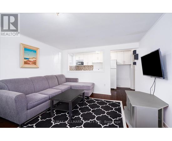 A living room with a grey couch and a painting of a beach scene on the wall.