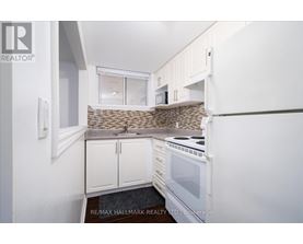 A kitchen with white cabinets and a stone backsplash.