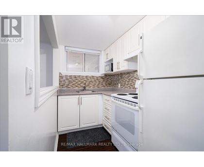 A kitchen with white cabinets and a stone backsplash.