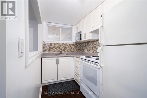 A kitchen with white cabinets and a stone backsplash.