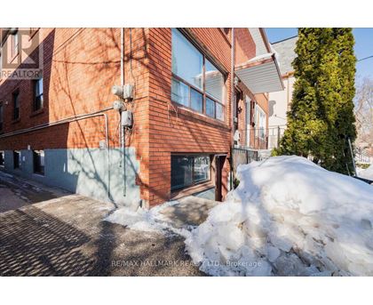 A red brick building with a snow pile in front.