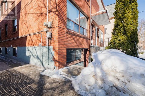 A red brick building with a snow pile in front.